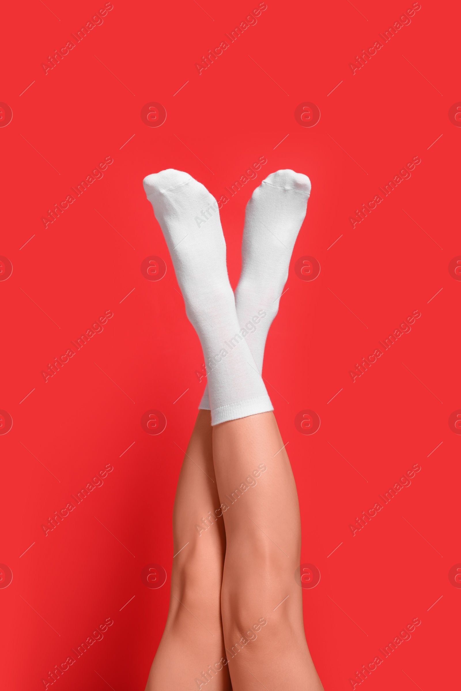 Photo of Woman in stylish white socks on red background, closeup