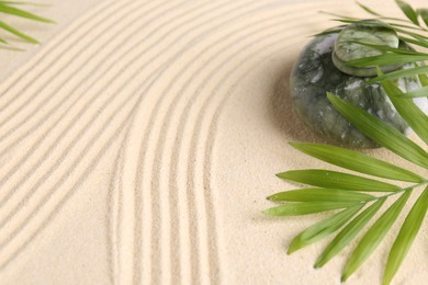 Photo of Zen concept. Stone, leaves and pattern on beige sand, closeup. Space for text