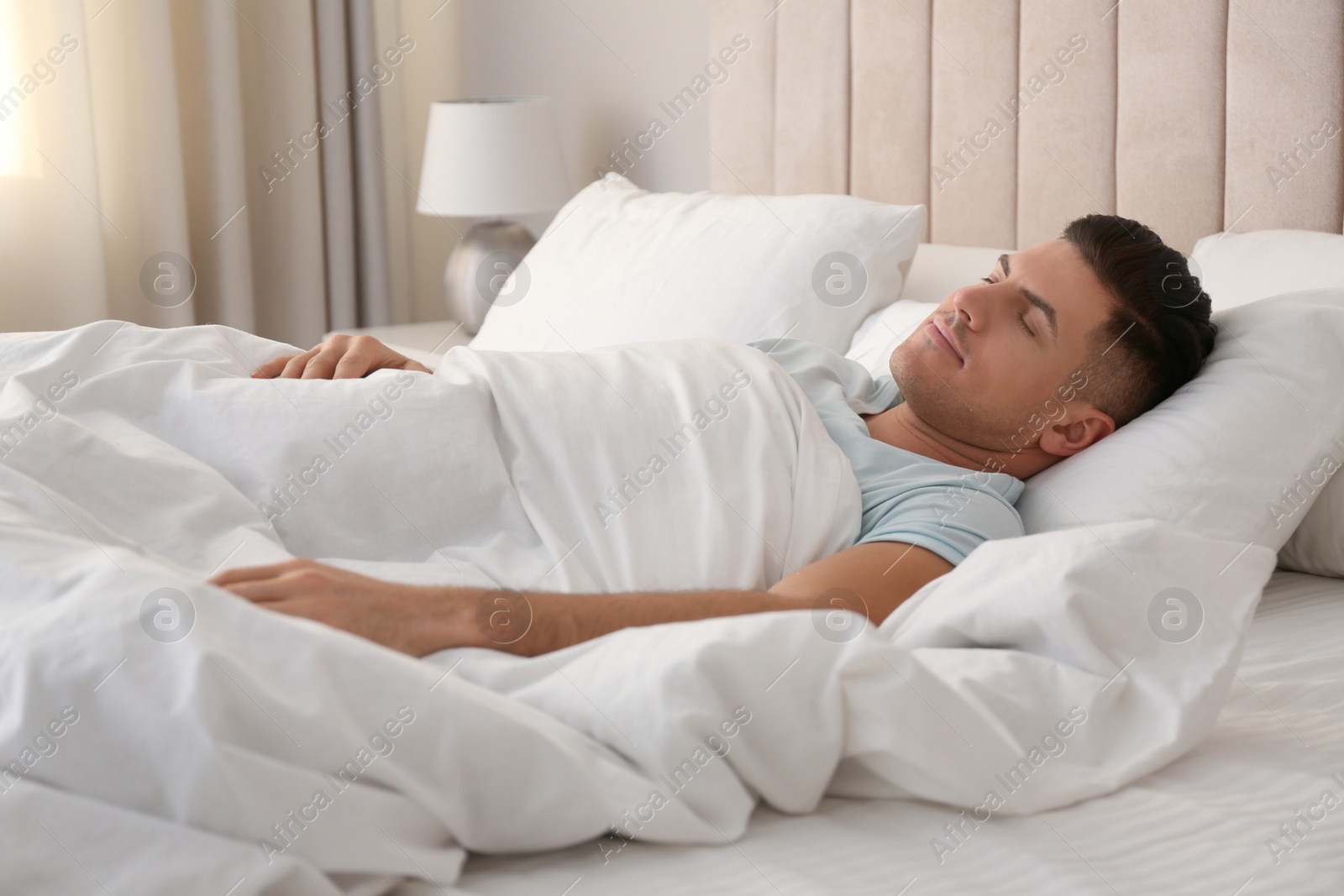 Photo of Man sleeping in bed with white linens at home