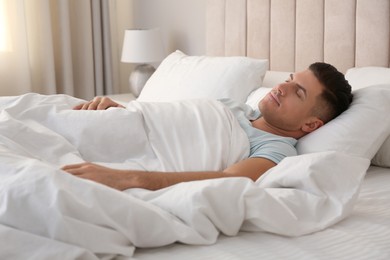 Man sleeping in bed with white linens at home