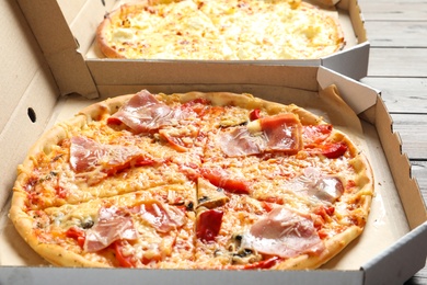 Carton boxes with delicious pizzas on wooden background