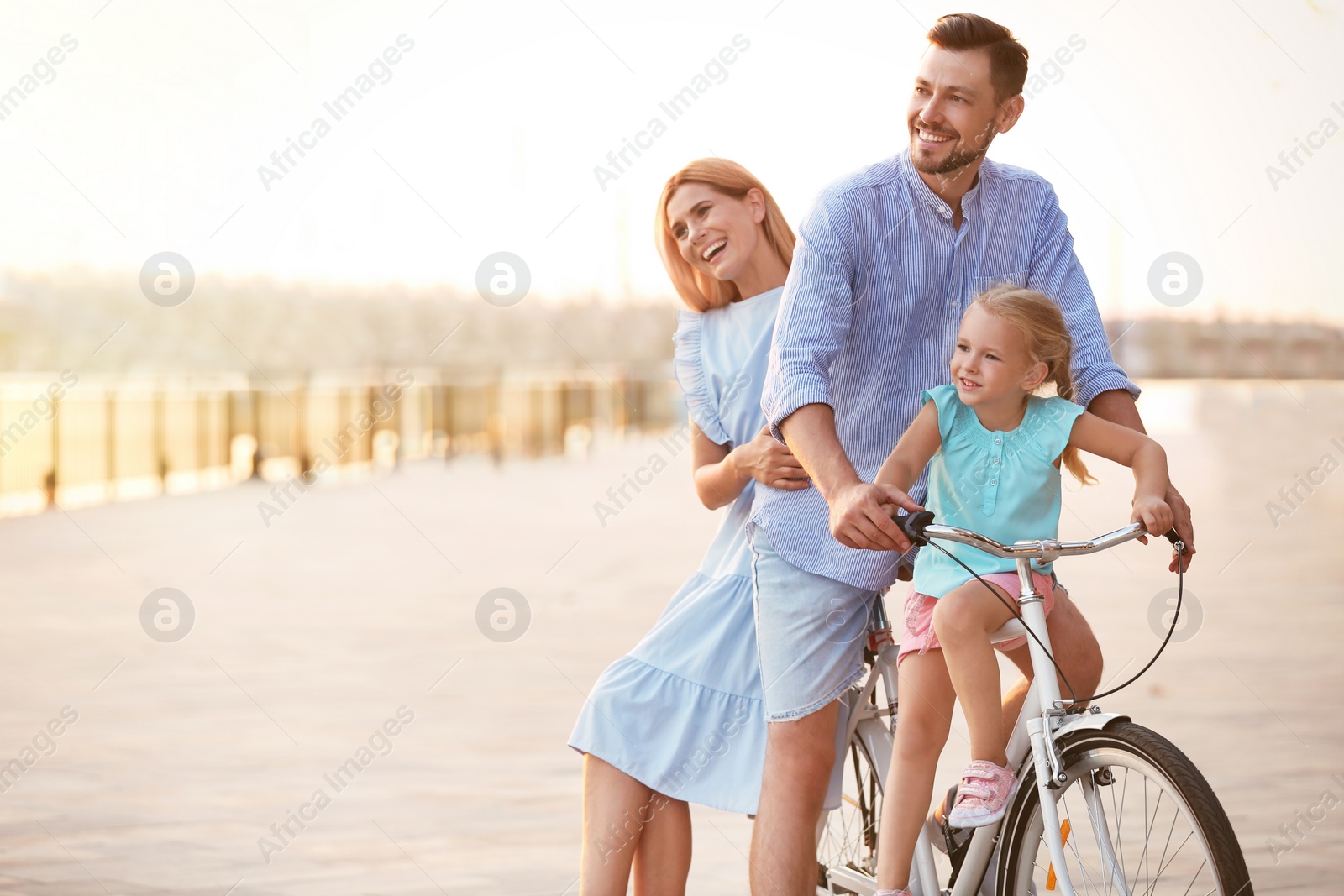 Photo of Happy family riding bicycle outdoors on summer day