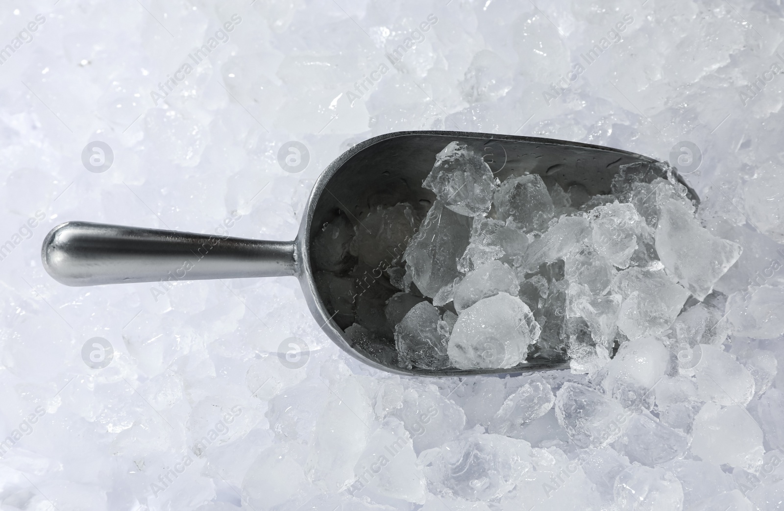 Photo of Metal scoop on crushed ice, top view