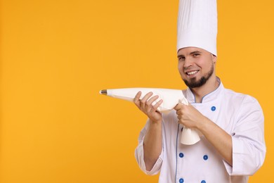 Photo of Happy professional confectioner in uniform holding piping bag on yellow background. Space for text