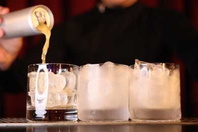 Photo of Bartender pouring energy drink into glass at counter in bar, closeup