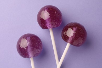 Tasty lollipops on violet background, flat lay