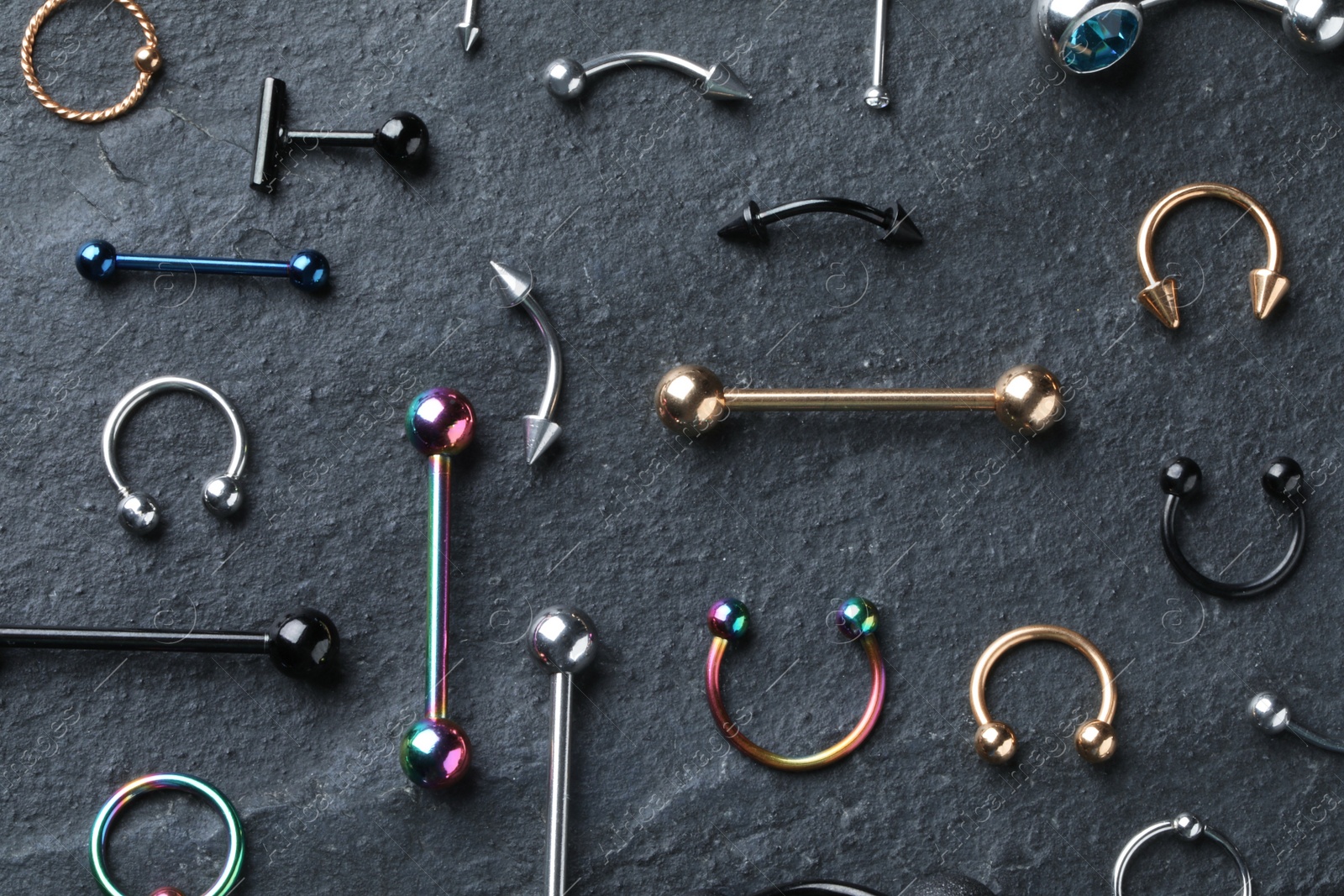 Photo of Stylish piercing jewelry on grey table, flat lay