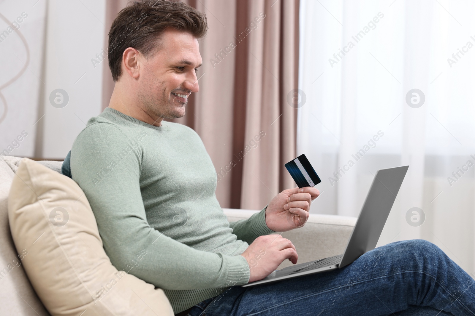 Photo of Man with credit card using laptop for shopping online at home