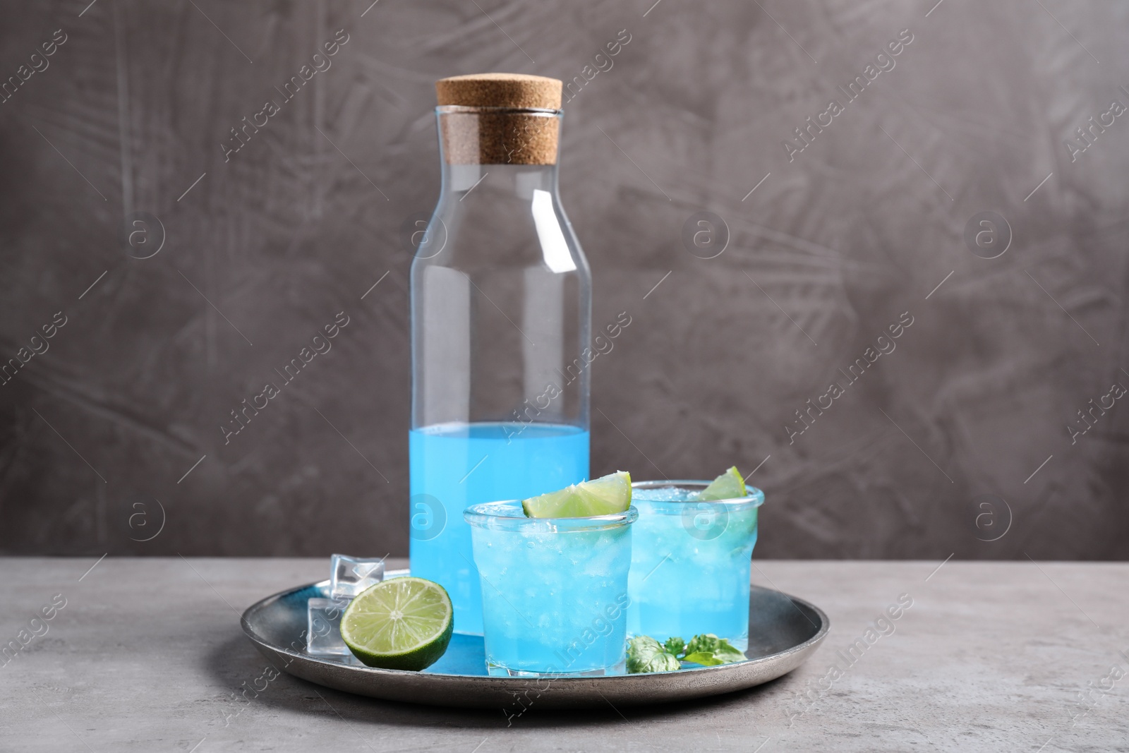 Photo of Tasty fresh light blue drink with lime on grey table