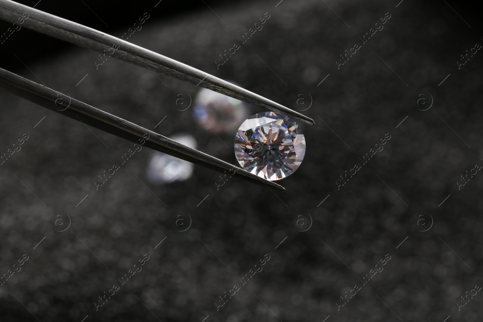 Photo of Tweezers with beautiful shiny diamond on dark background, closeup