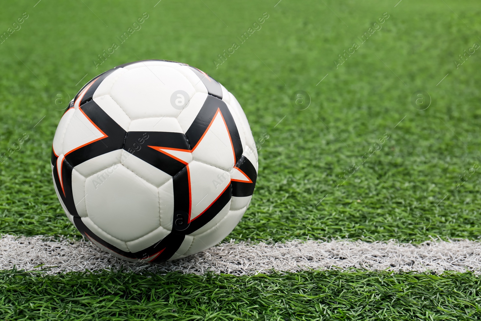 Photo of New soccer ball on green football field, space for text