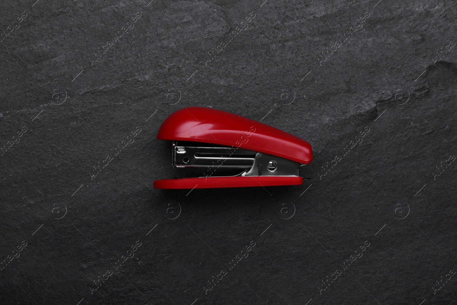 Photo of New bright stapler on black table, top view. School stationery