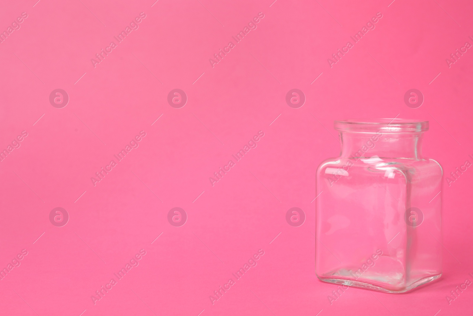 Photo of Open empty glass jar on pink background, space for text