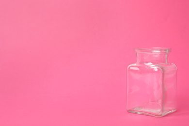 Photo of Open empty glass jar on pink background, space for text