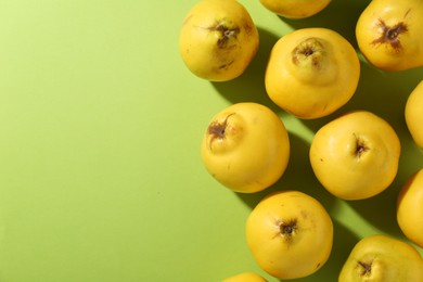 Tasty ripe quinces on light green background, flat lay. Space for text