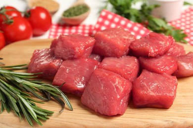 Photo of Cooking delicious goulash. Raw beef meat and rosemary on wooden board, closeup