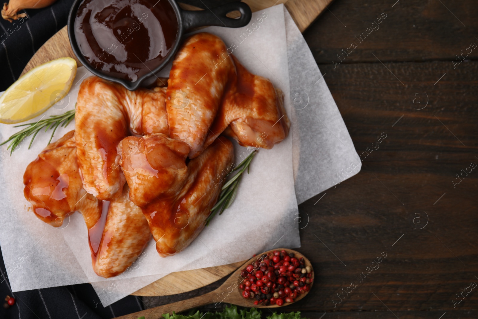 Photo of Fresh marinade, raw chicken wings and spices on wooden table, top view. Space for text