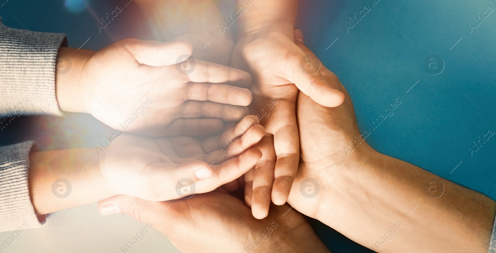 Image of Happy family holding hands on blue background, top view. Banner design 