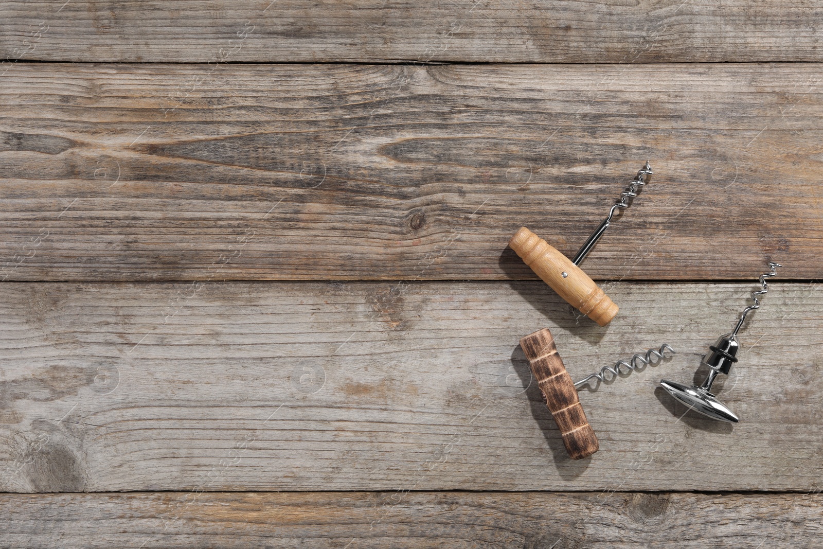 Photo of Different corkscrews on wooden table, flat lay. Space for text