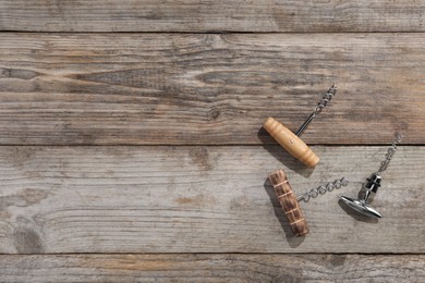 Different corkscrews on wooden table, flat lay. Space for text