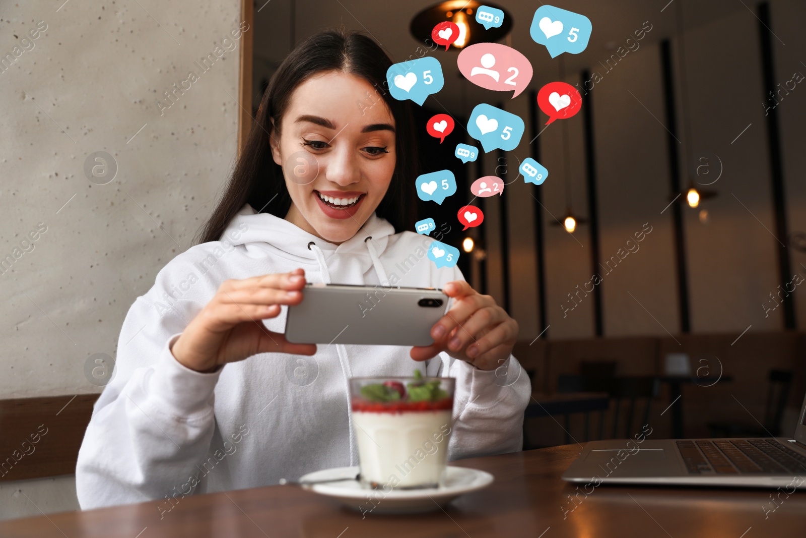 Image of Young blogger taking picture of dessert at table in cafe