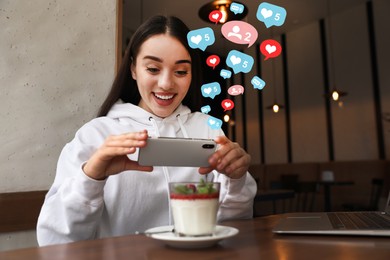 Image of Young blogger taking picture of dessert at table in cafe