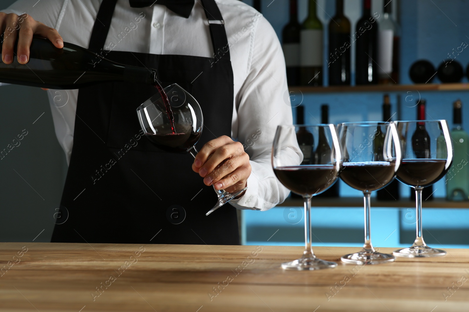 Photo of Bartender pouring wine into glass at counter in restaurant, closeup