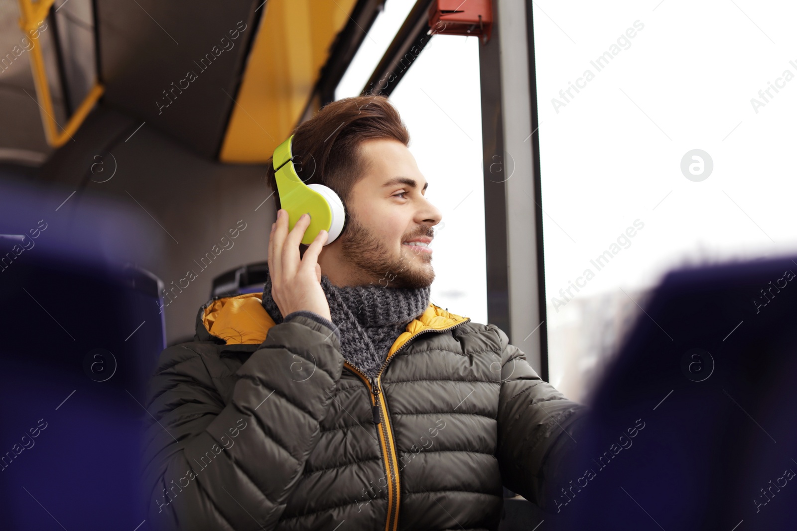 Photo of Young man listening to music with headphones in public transport