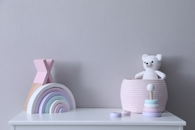 Child's toys on chest of drawers near light grey wall indoors