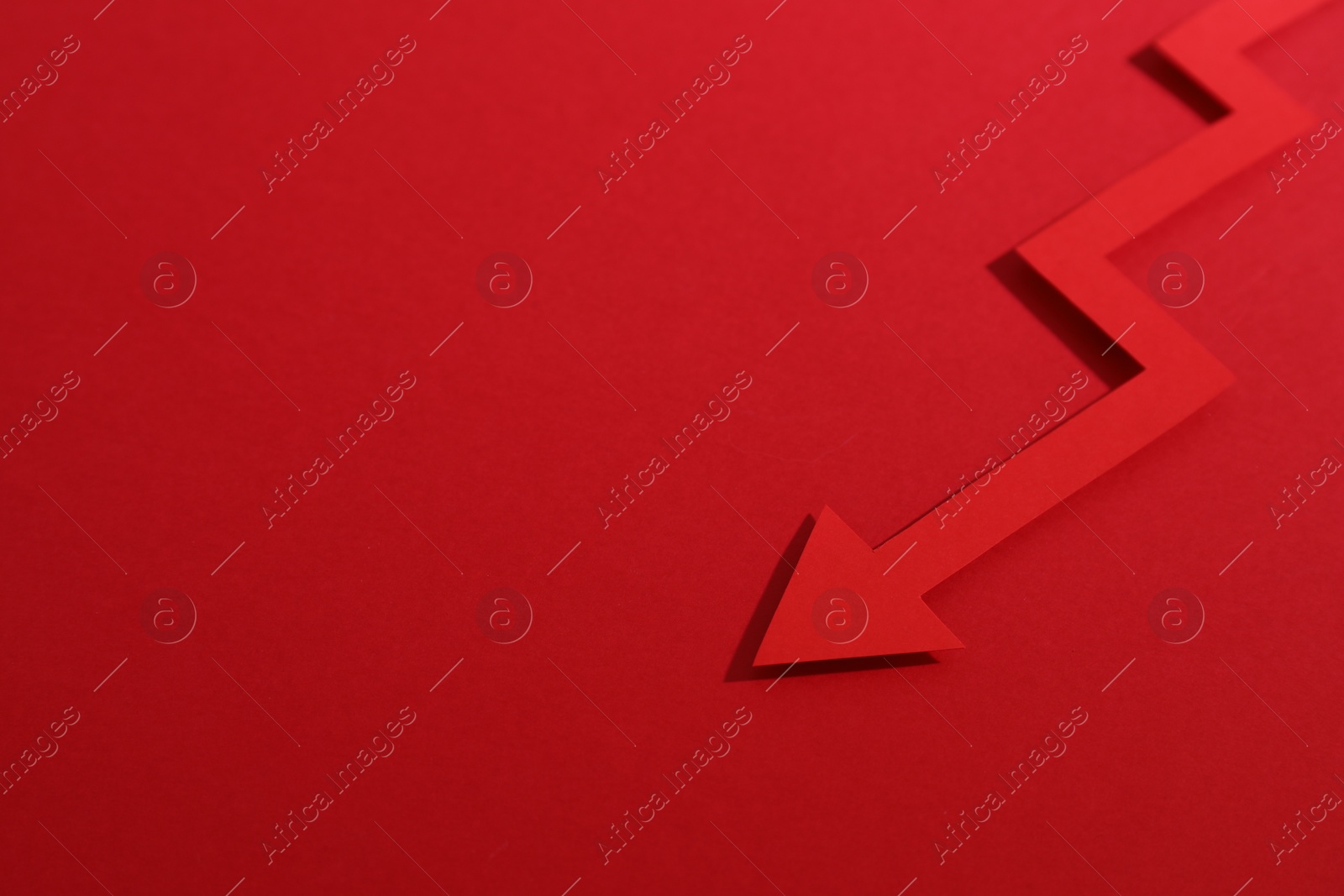 Photo of One zigzag paper arrow on red background, closeup. Space for text