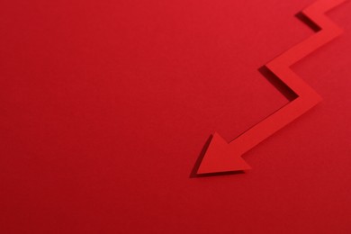 Photo of One zigzag paper arrow on red background, closeup. Space for text