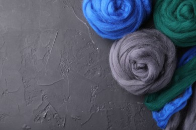 Photo of Colorful felting wool on dark textured table, flat lay. Space for text