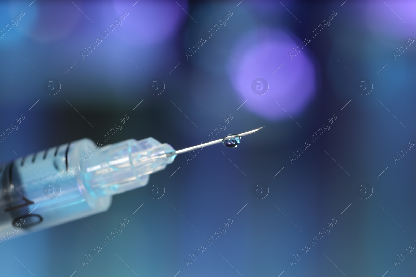 Photo of Syringe with medicine against blurred background, closeup. Space for text