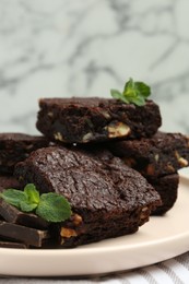 Photo of Delicious chocolate brownies with nuts and fresh mint on napkin, closeup