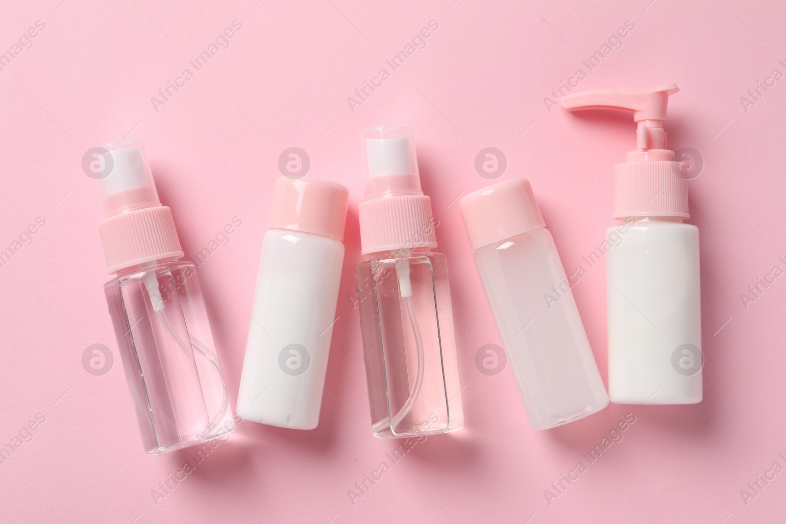 Photo of Cosmetic travel kit on pink background, flat lay. Bath accessories