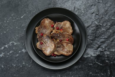 Photo of Tasty beef tongue pieces on black textured table, top view