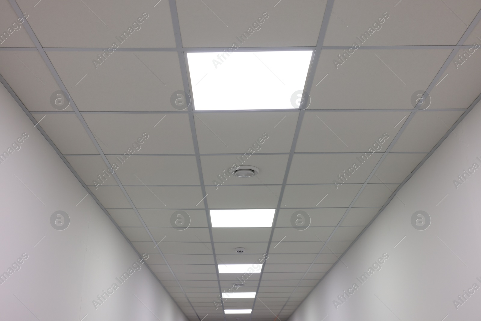 Photo of White ceiling with PVC tiles and lighting indoors, low angle view