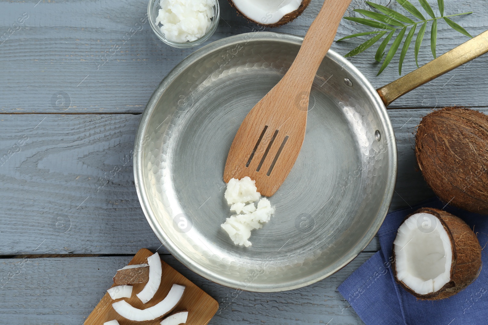 Photo of Flat lay composition with frying pan and organic coconut cooking oil on grey wooden table