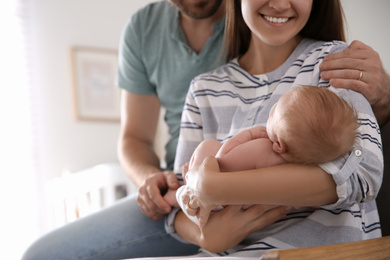 Photo of Happy couple with their newborn baby at home, closeup