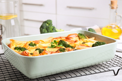 Tasty broccoli casserole in baking dish on cooling rack indoors