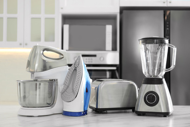 Photo of Set of modern home appliances on white marble table in kitchen