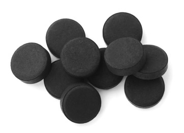 Photo of Activated charcoal pills on white background, top view. Potent sorbent