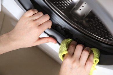 Photo of Top view of woman cleaning washing machine with rag, closeup