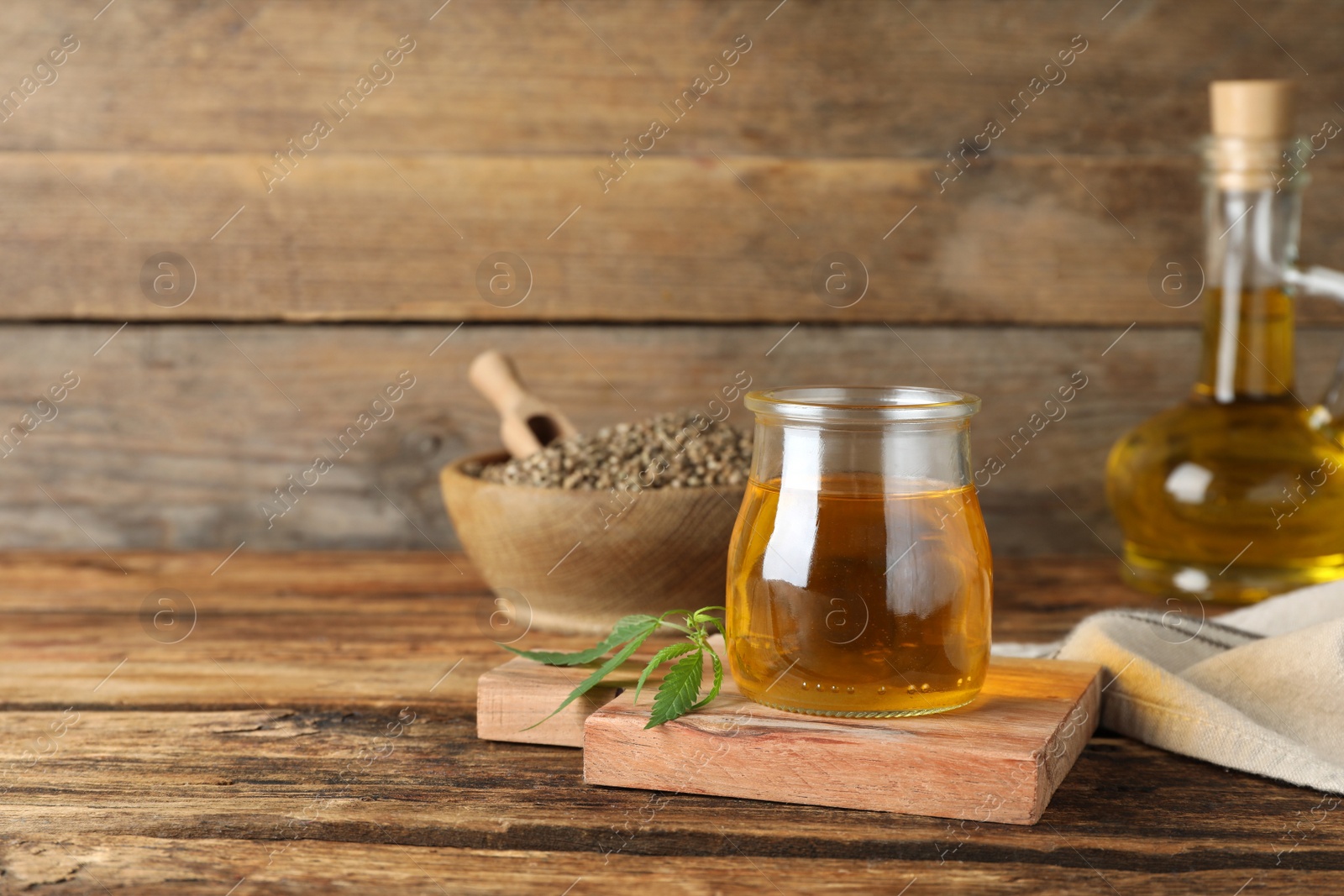 Photo of Hemp oil and leaves on wooden table. Space for text