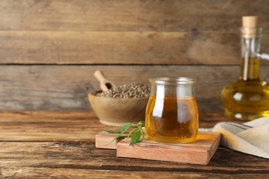 Photo of Hemp oil and leaves on wooden table. Space for text