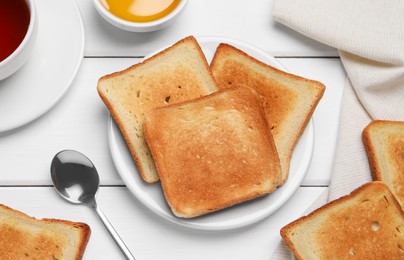 Slices of tasty toasted bread and aromatic tea on white wooden table, flat lay