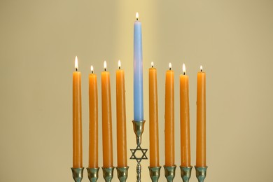 Hanukkah celebration. Menorah with burning candles on beige background, closeup