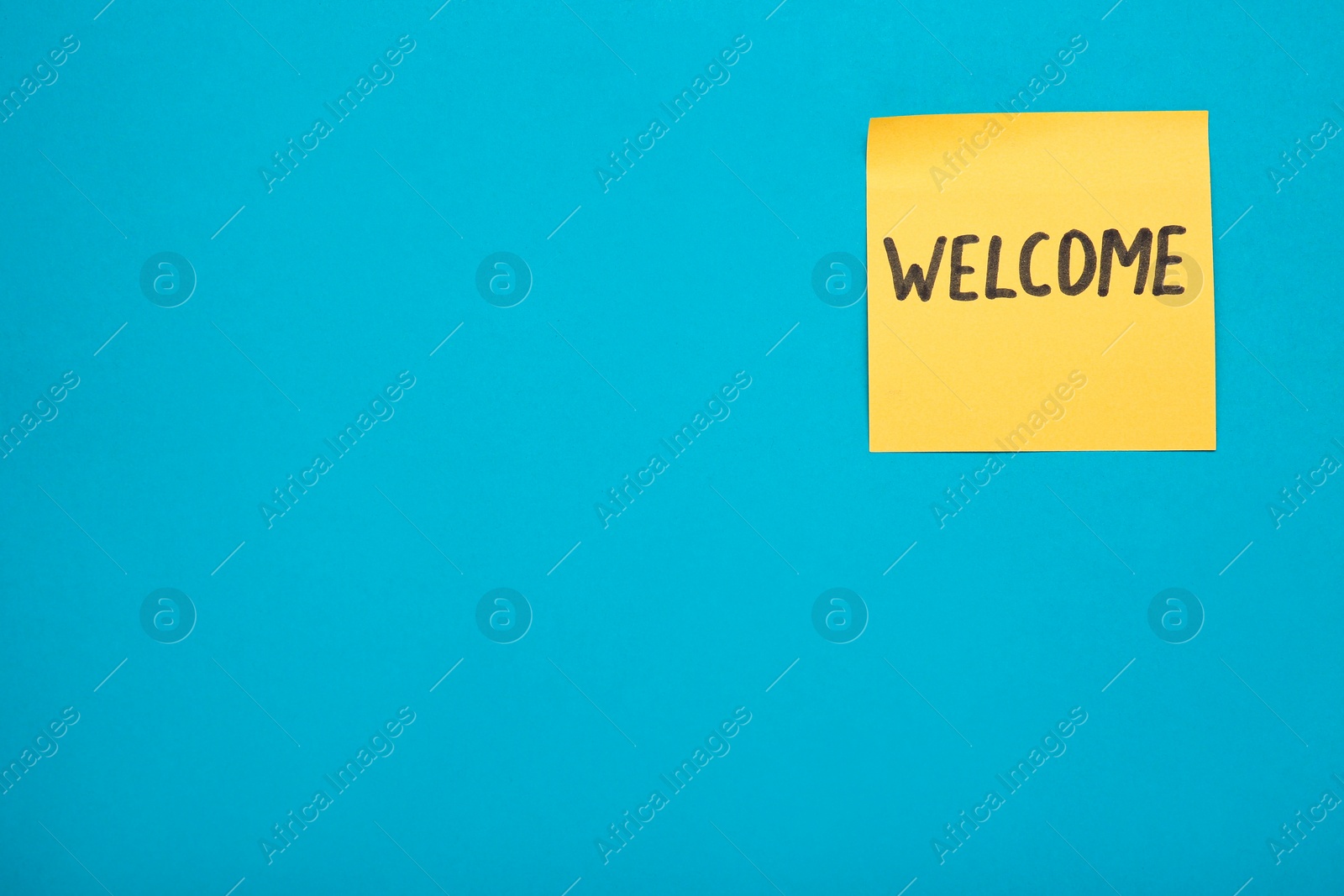 Photo of Paper note with word Welcome on turquoise background, top view. Space for text