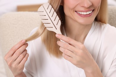 Photo of Happy woman brushing her hair in room, closeup