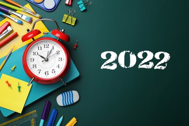 Image of Back to school 2022. Flat lay composition with alarm clock and different stationery on green chalkboard